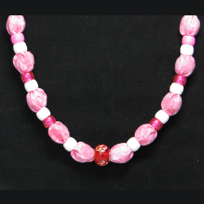 This necklace has red and white pony beads and a red glass with flower bead in the center.  The fabric is multi-colored pinks with glittery sparkles.