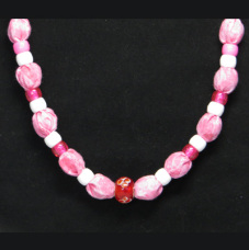 This necklace has red and white pony beads and a red glass with flower bead in the center. The fabric is multi-colored pinks with glittery sparkles.