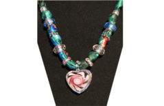 Green silky fabric necklace with small glass heart with rose painted on it.