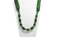 A Christmas necklace with gold pattern on a dark green cotton fabric with pony beads
