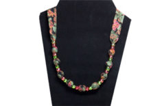 An elegantly rich looking simple necklace with green and rose pony beads with grapes and leaves on black cotton fabric.