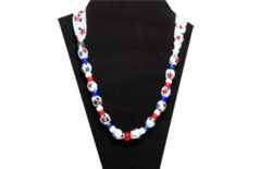 This patriotic necklace has lots of red and blue stars on white cotton fabric. The necklace has a red glass bead in the center, two silver tone metal stars and red white and blue pony beads.