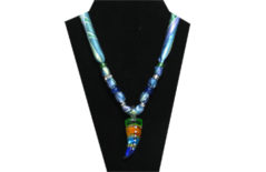 This necklace has a multi-colors dagger-like glass pendant of deep blue, turquoise, gold and green colors with clear rhinestones inset in the center. The fabric is silky green, blue and purple leaf pattern. The beads are silver tone, dark blue glass and clear rhinestone.