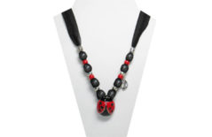 The necklace has a red and black metal ladybug pendant. The fabric is sheer black with sparkles. The beads are silver tone, red pony, and has a silver ton leaf charm.