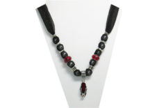 This necklace has a silver tone metal flip-flop pendant with garnet looking insole and a clear and red rhinestone flower on the strap. The fabric is black sheer sparkly with beads that are silver tone metal and garnet color faceted beads.