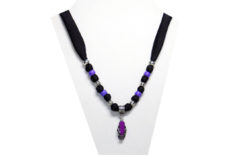 This necklace has a small purple flip-flop pendant with silver tone metal strap and flower. The fabric is black silky with beads of silver tone and purple pony beads.