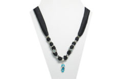 This necklace has a small silver tone metal flip-flop with a turquoise sole and clear rhinestones on the strap and sole. The fabric is black silky with beads that are silver tone metal, and silver tone metal flower with turquoise rhinestones.