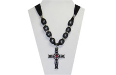A beautiful cross necklace with sparkly sheer black fabric ties. The cross pendant is silver tone metal with inset black rhinestones and a red rhinestone in the center. The beads are designed of silver tone metal and clear rhinestones.