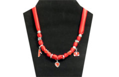 This necklace has red silky fabric with red beads and silver charms (hearts, shoe and purse). Other silver tone beads on the necklace and red rhinestone in silver tone metal.