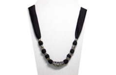 This simple but elegant necklace is a black and silver metal tube with a wrought iron design. The silky black fabric has accents of silver tone metal beads.